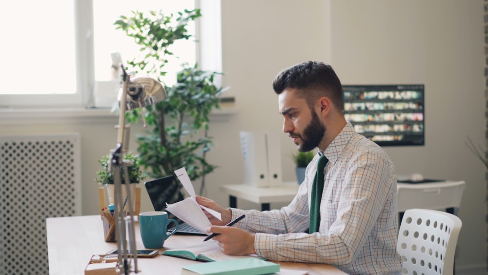 a man sitting at a desk with a laptop and papers