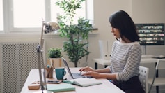 a woman sitting at a desk using a laptop computer