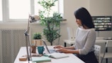 a woman sitting at a desk using a laptop computer