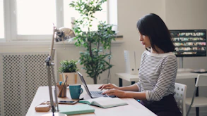 a woman sitting at a desk using a laptop computer