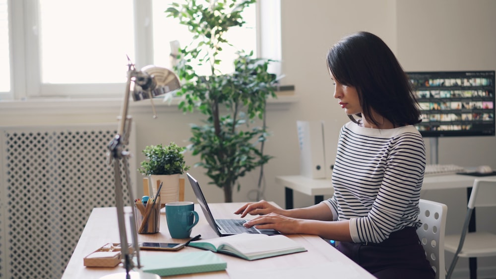 une femme assise à un bureau à l’aide d’un ordinateur portable