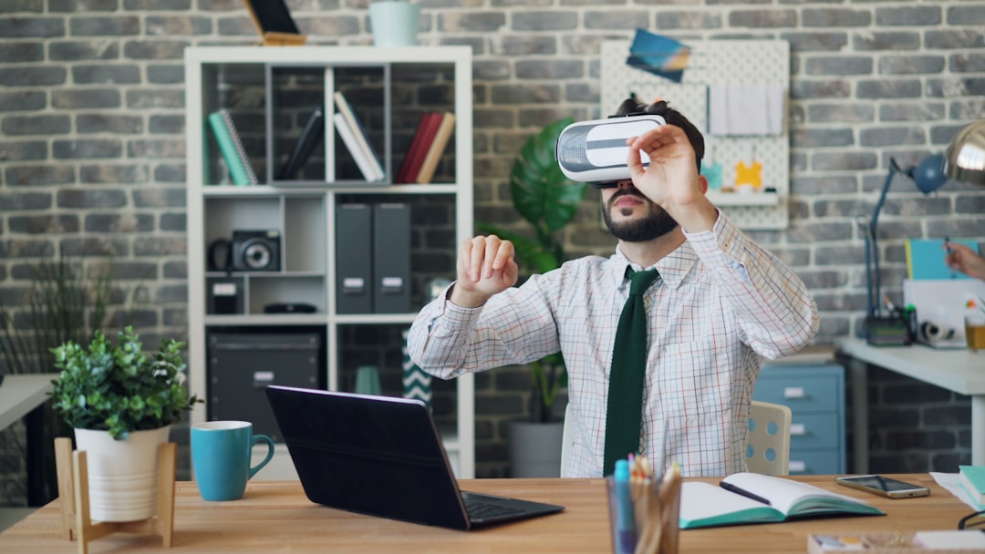 Young man using virtual reality glasses at work wearing headset gesturing