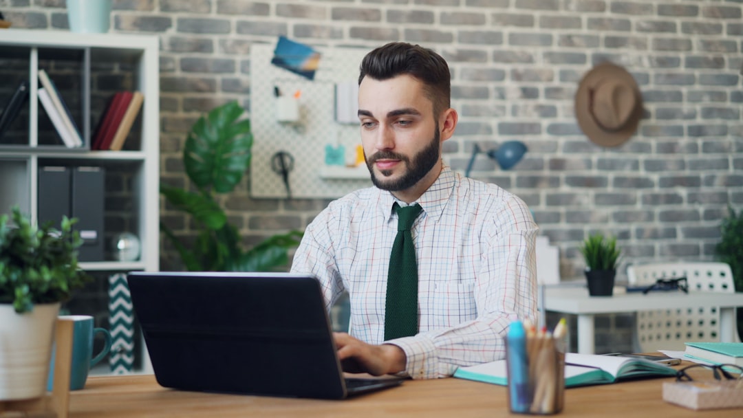 Portrait of young man working with laptop then looking at camera smiling