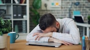 a man sitting at a desk with his head in his hands