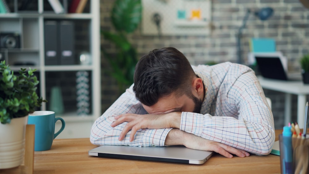 a man sitting at a desk with his head in his hands