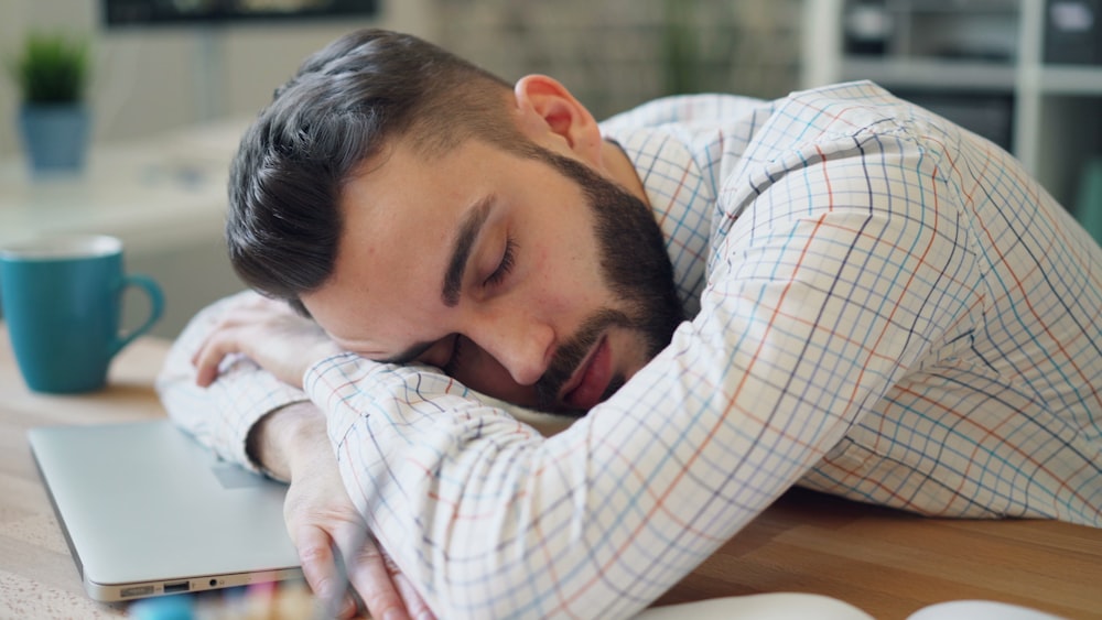 a man laying his head on his laptop