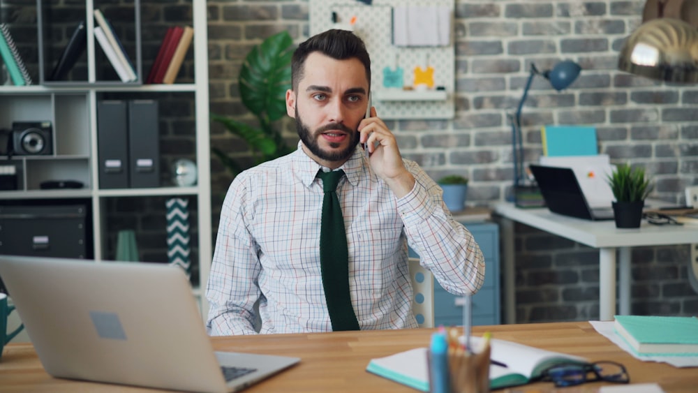 a man sitting at a desk talking on a cell phone