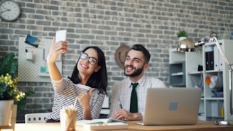 a man and a woman sitting at a table with a laptop