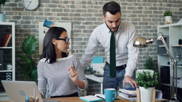 a man and a woman standing in front of a laptop