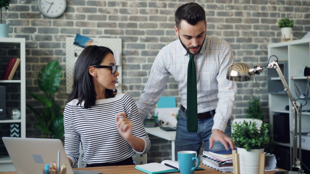 a man and a woman standing in front of a laptop