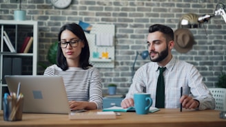 a man and a woman sitting at a table with a laptop