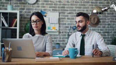 a man and a woman sitting at a table with a laptop
