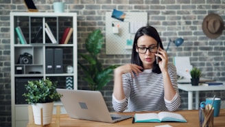 a woman sitting at a desk talking on a cell phone