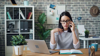 a woman sitting at a desk talking on a cell phone