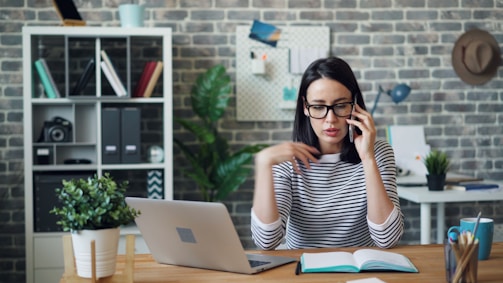 a woman sitting at a desk talking on a cell phone