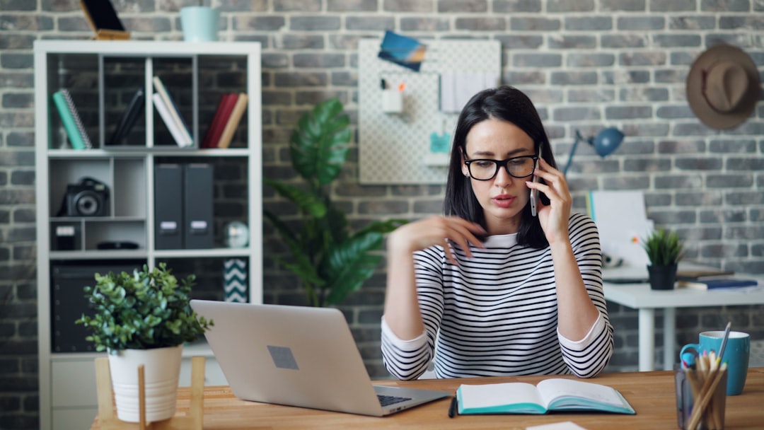 Angry young lady speaking on mobile phone in office discussing problems at work