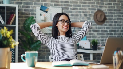 a woman sitting at a desk with her hands behind her head