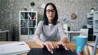 a woman sitting at a desk using a laptop computer