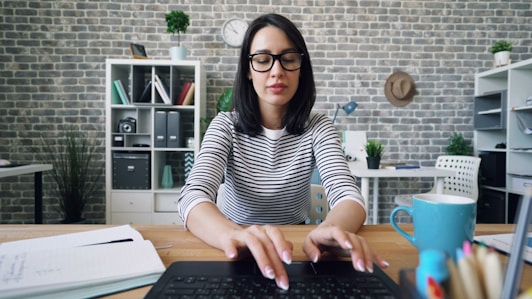 a woman sitting at a desk using a laptop computer