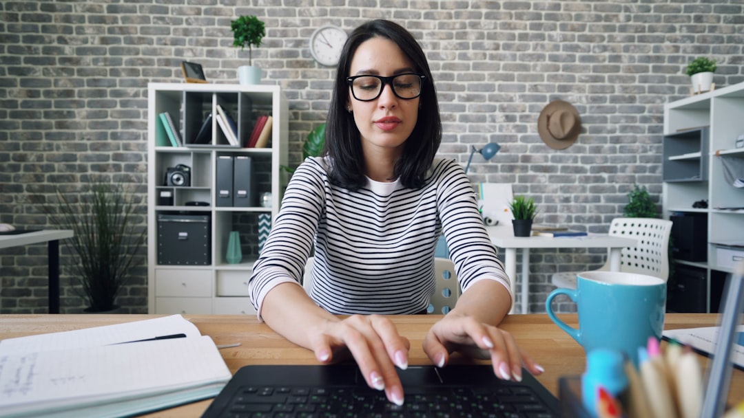 Portrait of beautiful girl using laptop typing sitting in office working alone