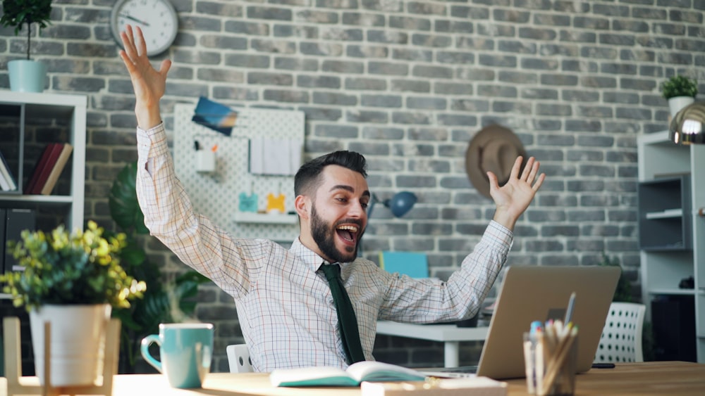 a man sitting at a desk with his arms in the air