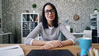 a woman sitting at a desk in front of a laptop