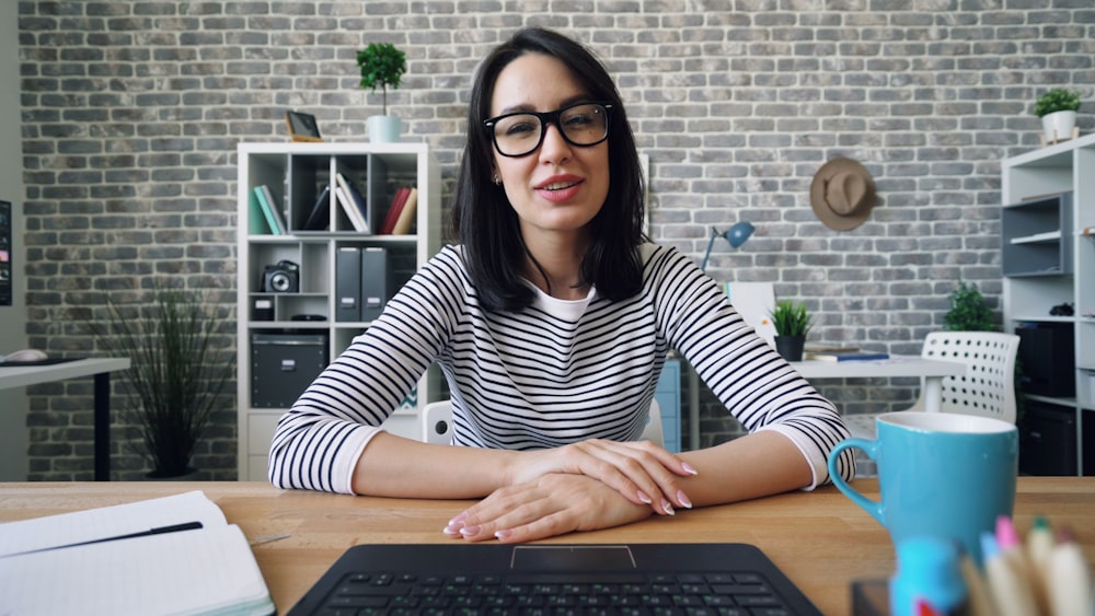 a woman sitting at a desk in front of a laptop