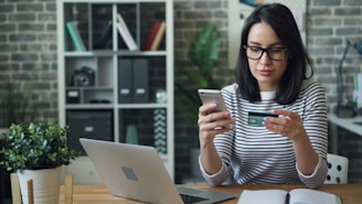 a woman sitting at a table looking at her cell phone