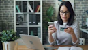 a woman sitting at a table looking at her cell phone