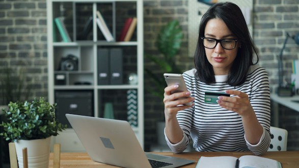 Mujer sentada a una mesa mirando su teléfono celular