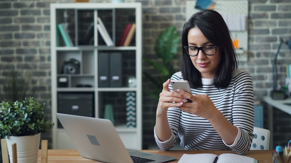 a woman sitting at a table looking at her cell phone