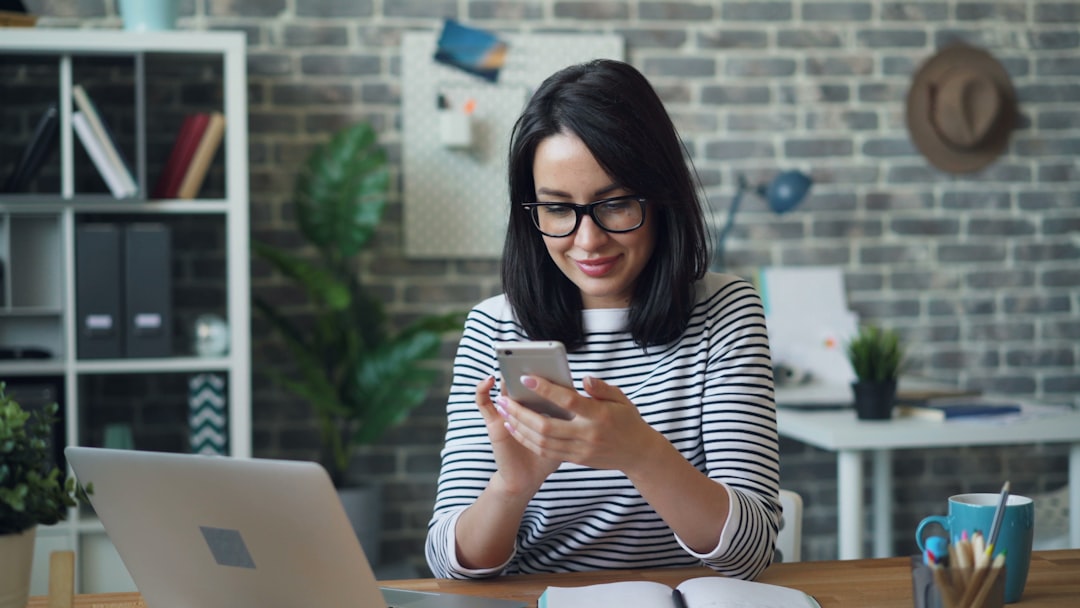 Beautiful woman using smartphone touching screen smiling in office