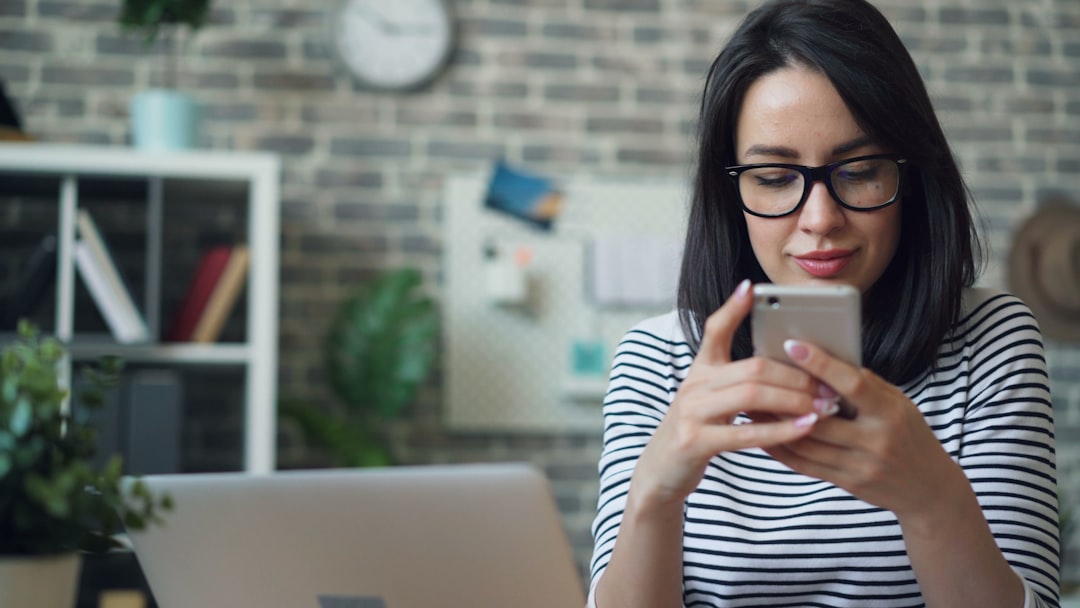 Beautiful woman using smartphone touching screen smiling in office