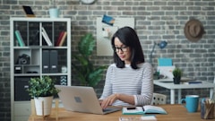 a woman sitting at a table using a laptop computer