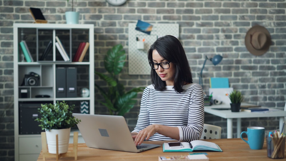 a woman sitting at a table using a laptop computer