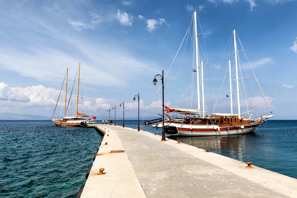 two boats are docked at the end of a pier