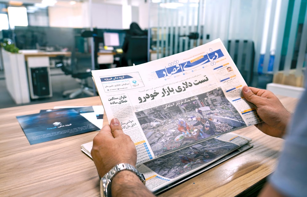 a man sitting at a table reading a newspaper