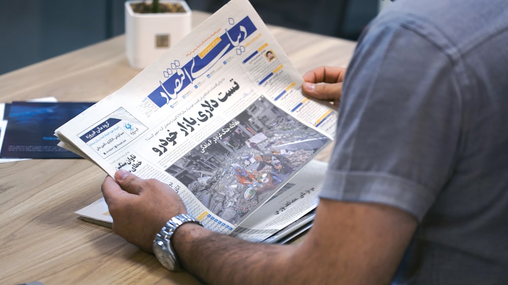 a man sitting at a table reading a newspaper