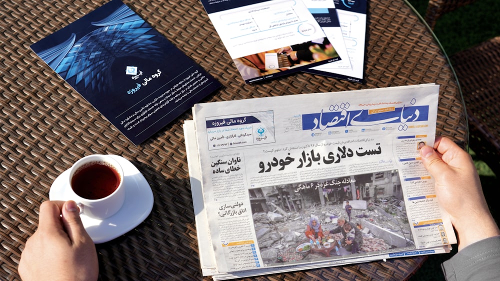 a person sitting at a table reading a newspaper