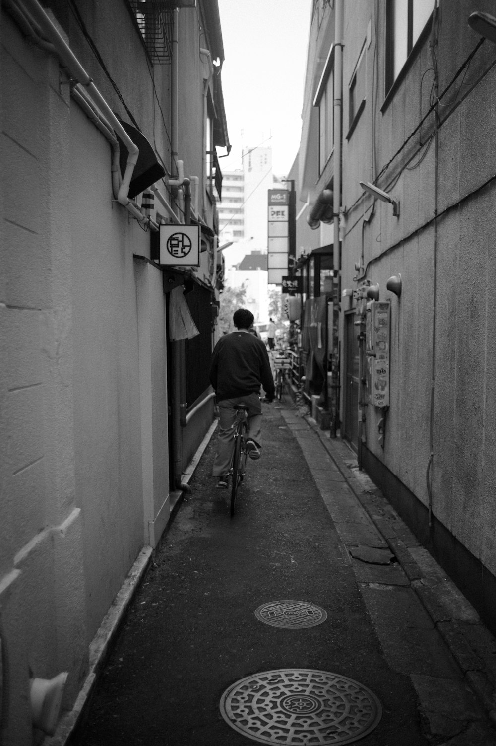 a man riding a bike down a narrow alley way