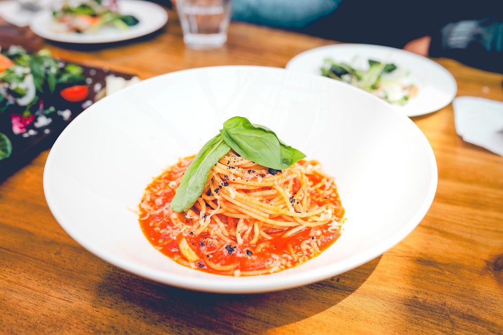 a plate of spaghetti with tomato sauce on a wooden table