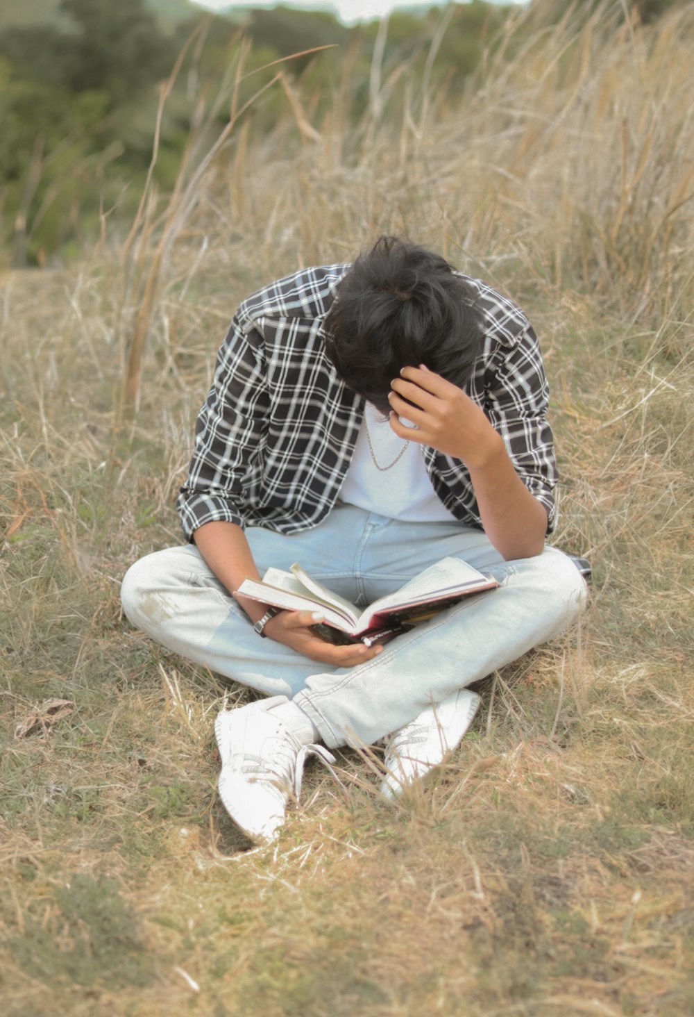 a man sitting in a field reading a book