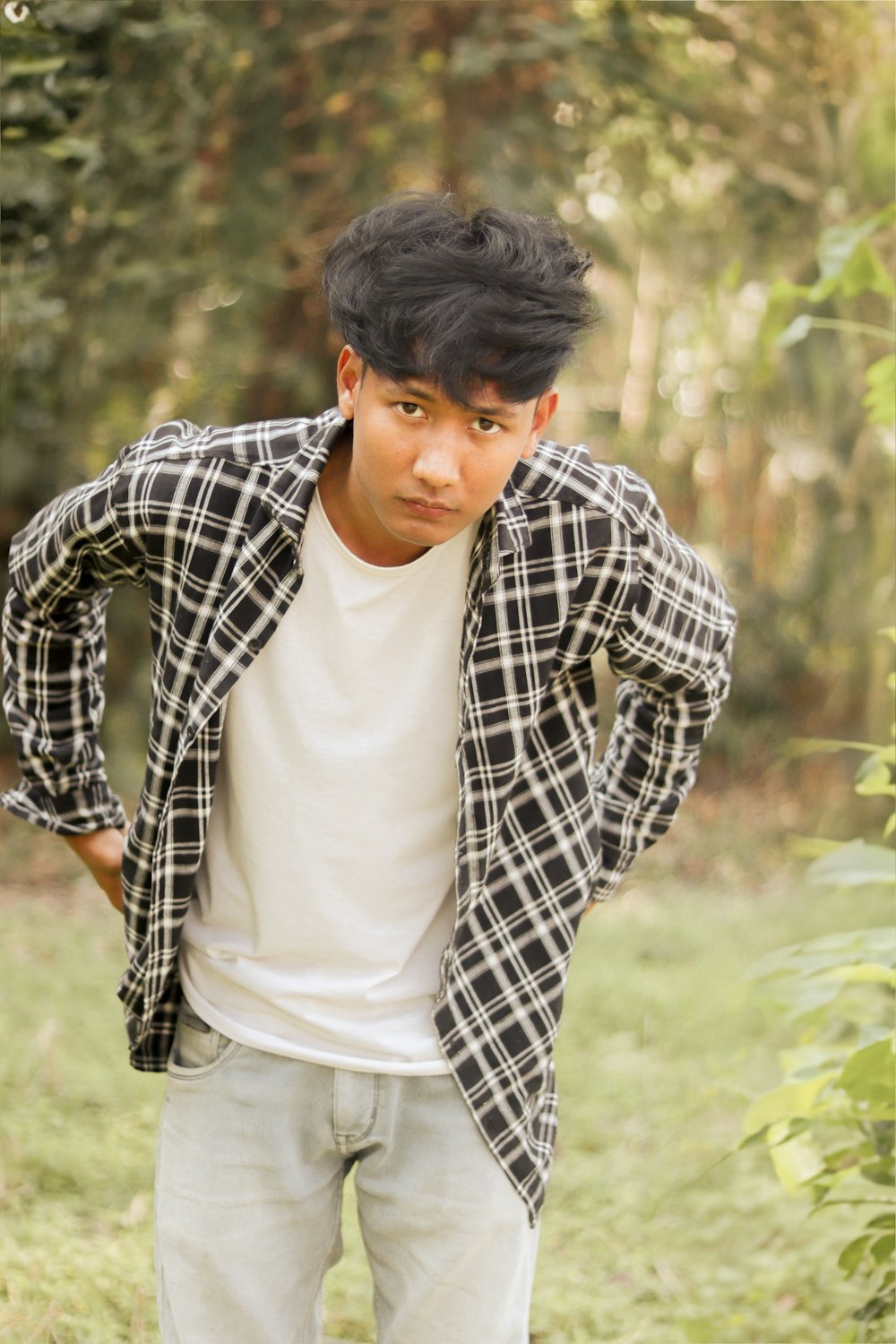 a young man standing in a field with his hands on his hips