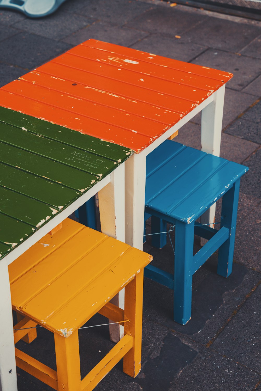 a table and two stools painted in different colors