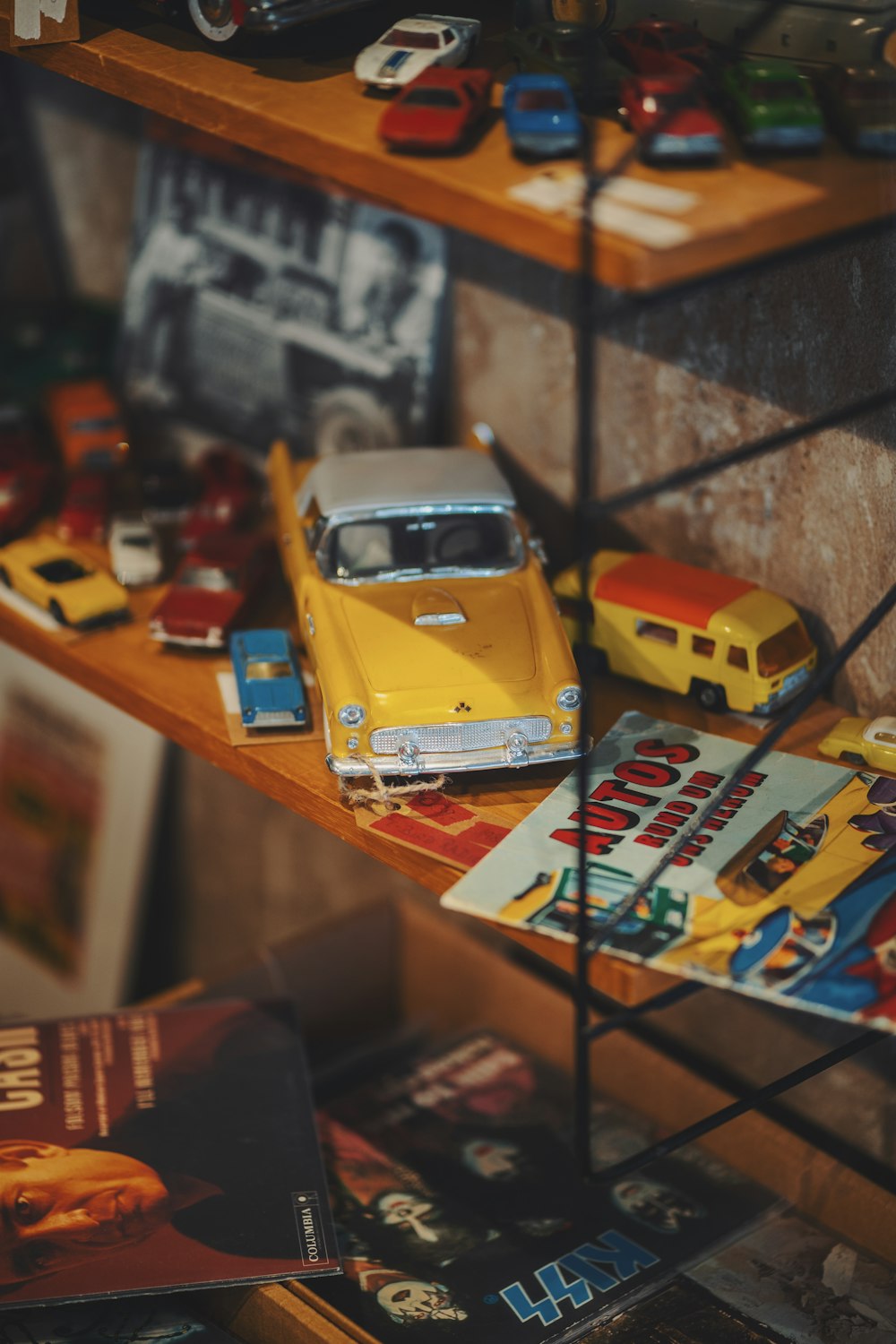 a yellow toy car sitting on top of a wooden shelf