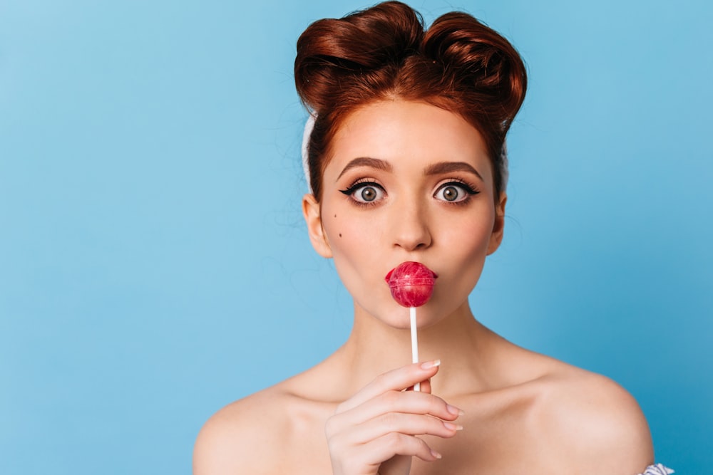 a woman holding a lollipop in front of her face