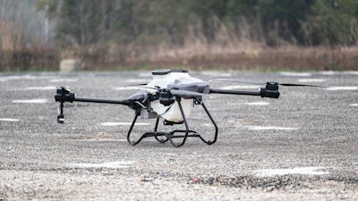 A black and white remote controlled flying device in a parking lot
