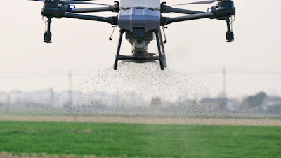 A small plane flying over a green field