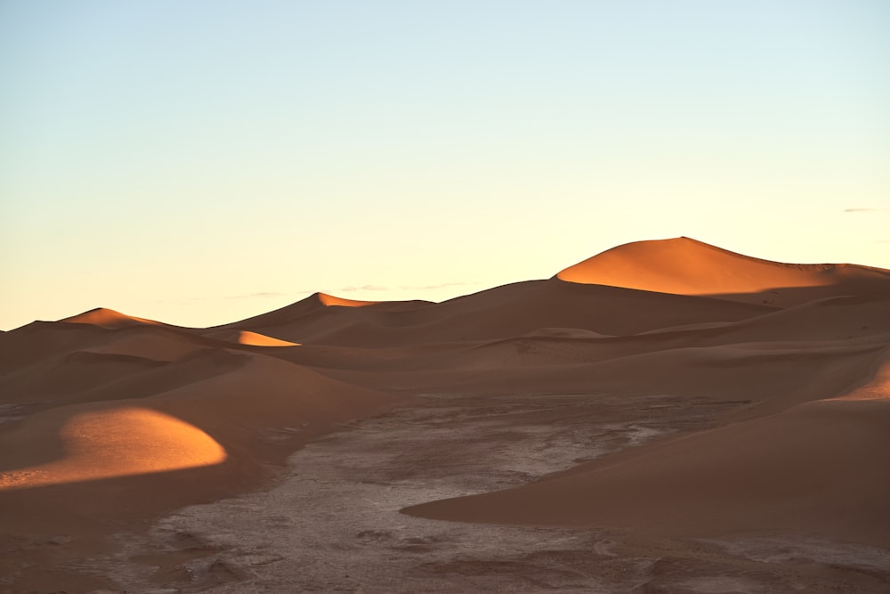 the sun is setting over the sand dunes