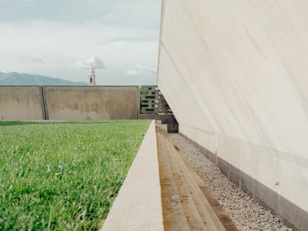 a grassy field with a concrete structure in the background